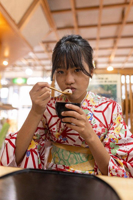 穿着和服的少女在日本餐馆吃白玉真哉红豆汤