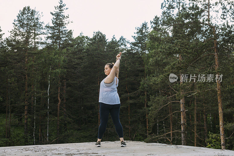 一名穿着运动服的白人女性在大自然中伸展时，目光移开