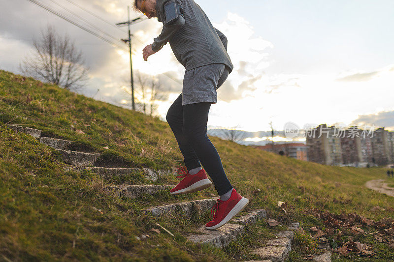 一个年轻男性跑步者在户外运动时跑上楼梯的特写镜头