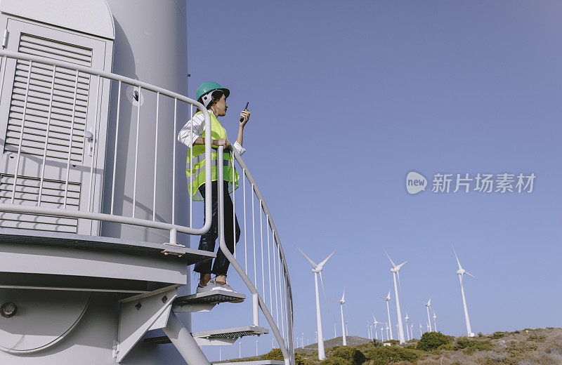 年轻的女工程师正在现场检查风力涡轮机