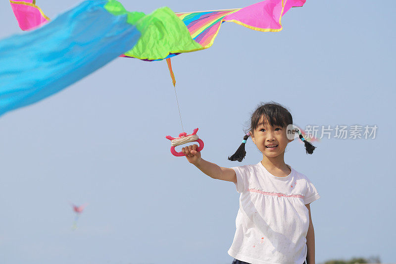 亚洲女孩在草地上玩和放风筝。