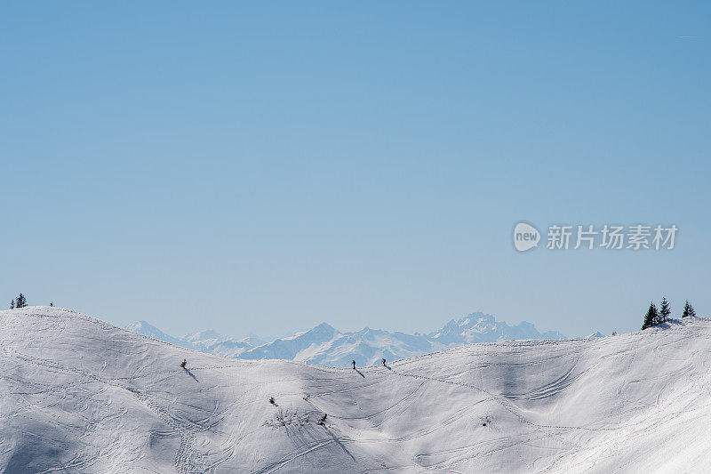 在法国阿尔卑斯山的雪景中，两个人穿着雪鞋的剪影