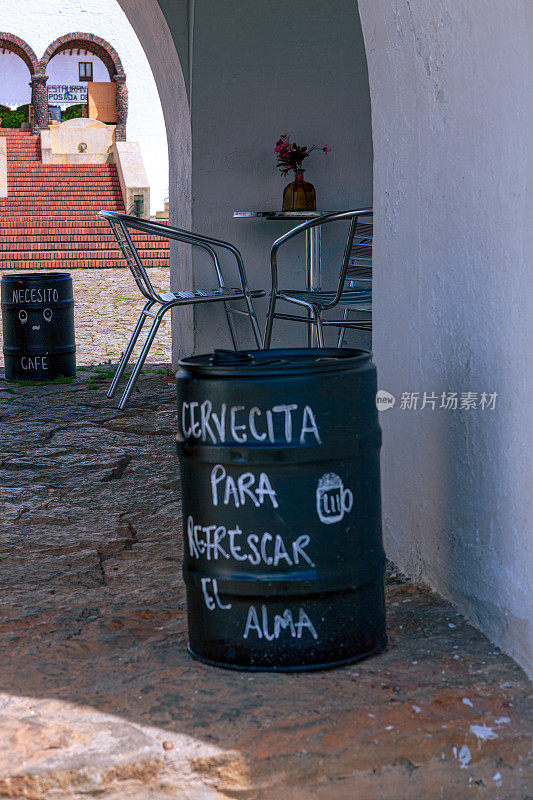 桶上手写的西班牙语标语翻译过来是:“来点啤酒提神。”这是邀请你进去买杯饮料。