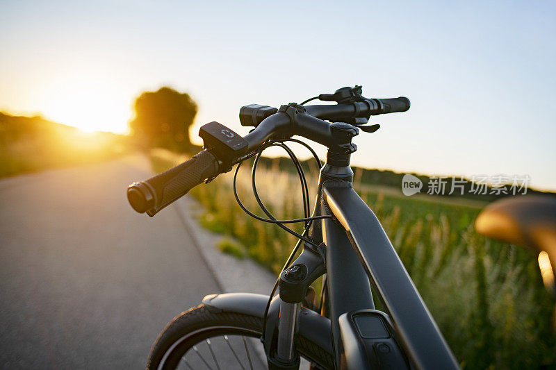 在夕阳西下的乡间小路上骑着电动自行车