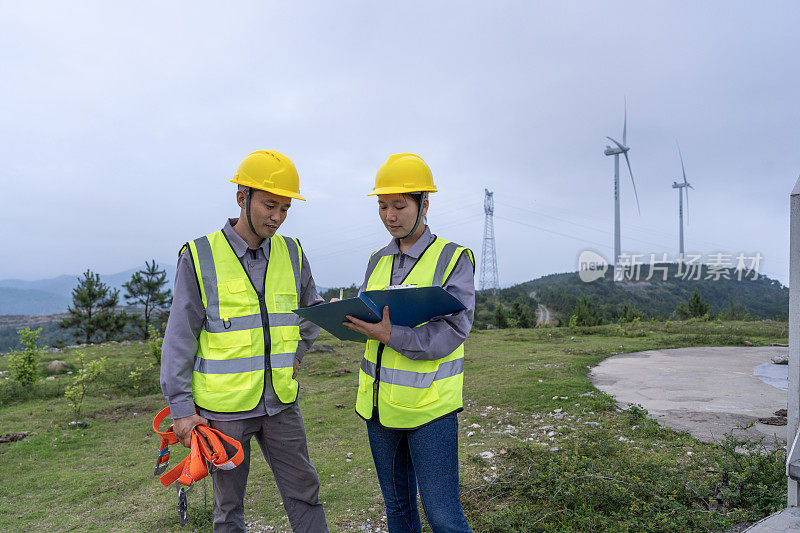 两个亚洲工程师在讨论风力涡轮机组的数据