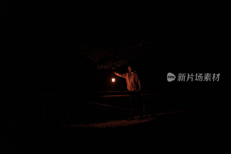 黄昏时分，一名男子手持红色灯泡在森林中行走