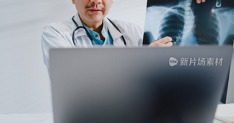 近距离的成熟亚洲男子医生使用笔记本电脑视频通话医疗结果在咨询病人在健康诊所。