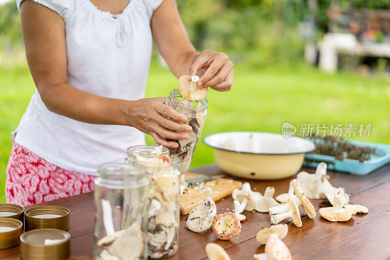 一个女人在罐子里保存蘑菇的特写