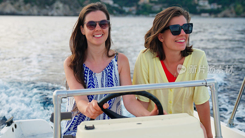 放松的女性朋友享受着梦想假期的快艇之旅。微笑着聊天拥抱