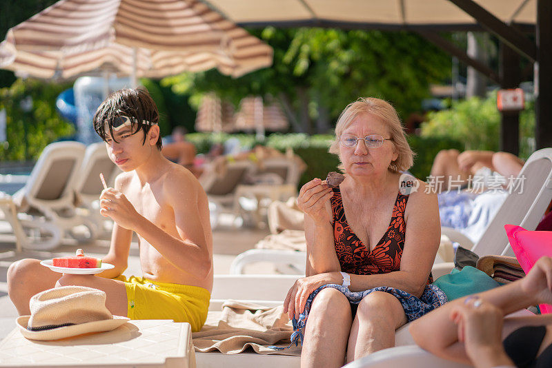 小男孩和奶奶在度假村泳池边吃冰淇淋