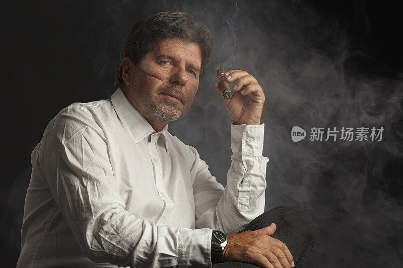 吸烟的高级男子拿着和享受他的古巴雪茄。疤痕的脸。的肖像