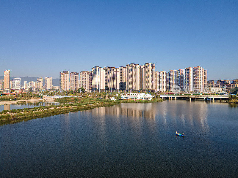 湖面倒映着现代城市建筑和蓝天