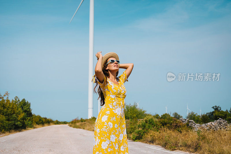 夏日里走过风力涡轮机的女人