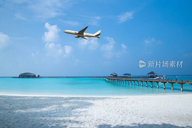 在一个阳光明媚的日子里，一架白色的飞机飞过热带海域和沙滩