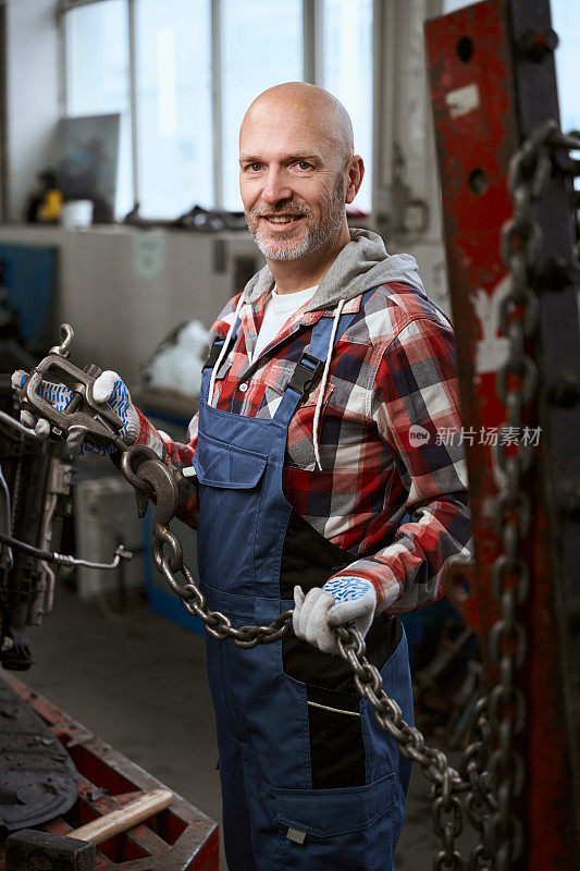 一个穿着格子衬衫的男人站在一家汽车修理店里