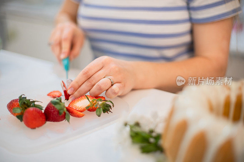 年轻女子切草莓和装饰春天的灵感kugelhopf蛋糕
