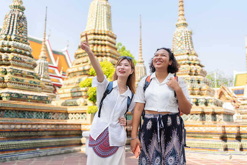 寺庙是一种能让心灵平静、放松的旅游景点。韩国人和非裔美国妇女的肖像，穿着休闲布，背着背包站在寺庙里。假期假期旅行期间的周末活动。参观寺庙，参观古建筑