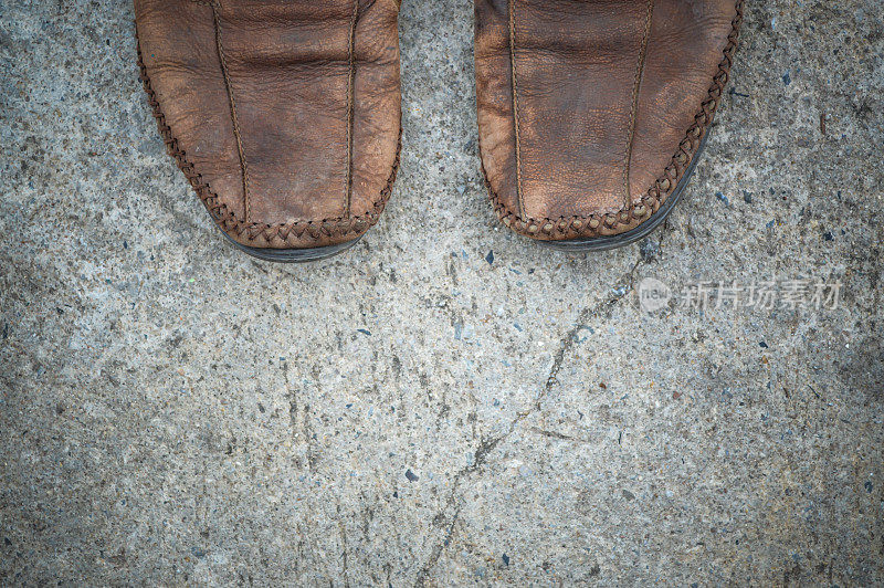 一半的皮鞋踩在水泥路面上