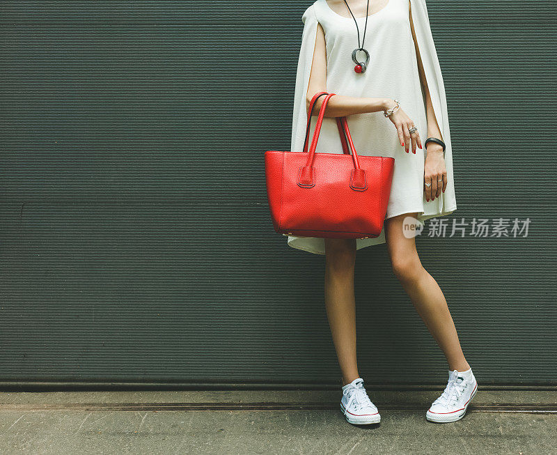 女孩手臂上挎着时尚的红色大手提包