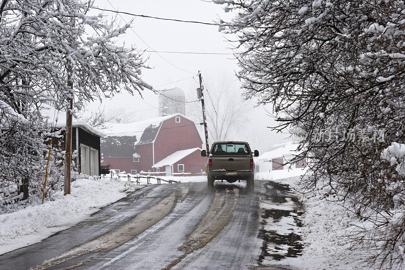 乡村公路在春天暴风雪与卡车和谷仓