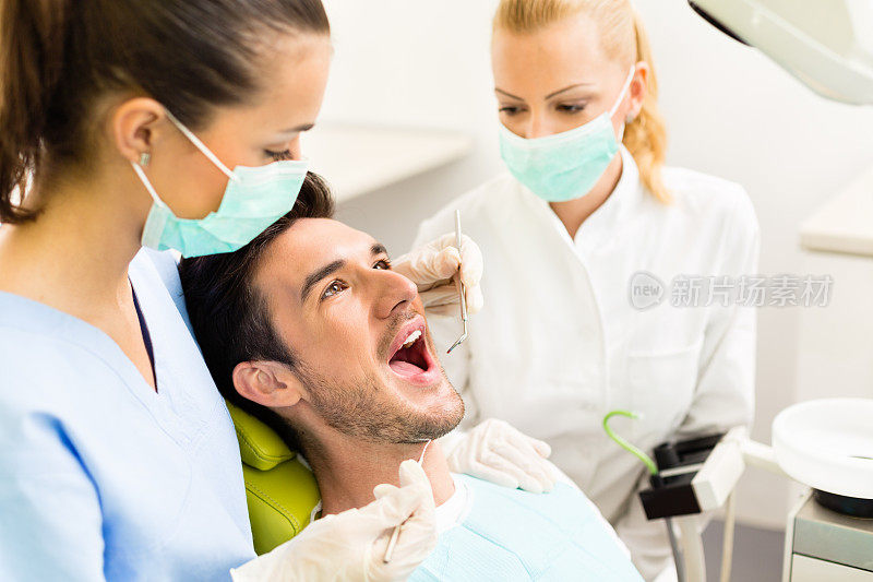 男病人在牙科诊所接受口腔检查前张口
