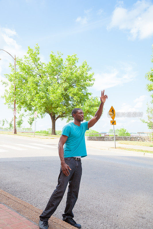 穿着t恤的高个子非洲裔美国人在人行道上招呼出租车