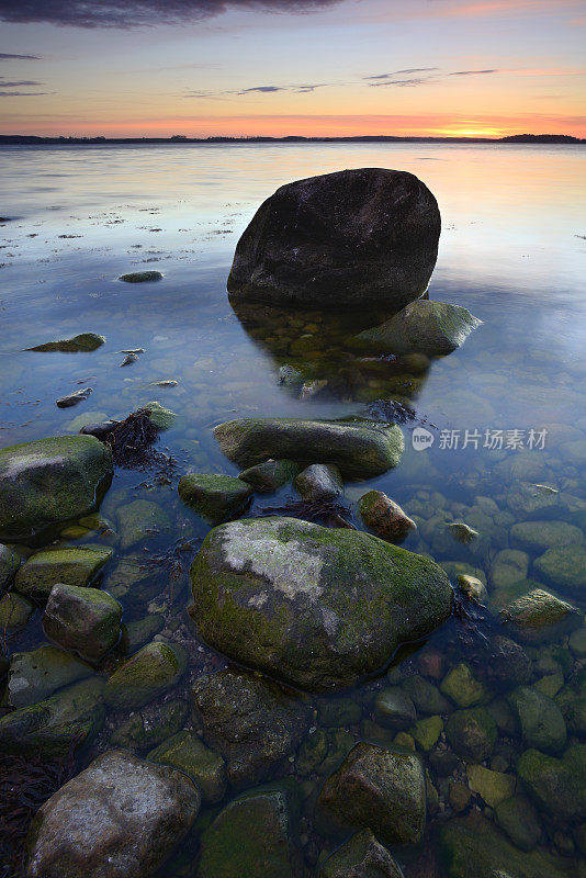 日落的海景与苔藓覆盖的巨石，鲁根岛，德国