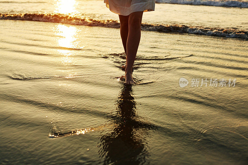 低段的女人走在潮湿的海岸