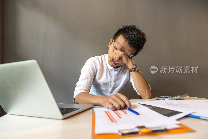 男人在笔记本电脑前看起来疲倦和昏昏欲睡