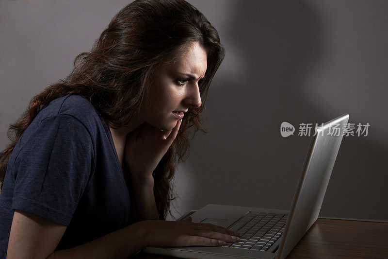 少女使用笔记本电脑与危险的阴影在背景