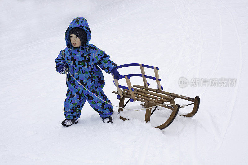 蹒跚学步的孩子在雪地里玩雪橇