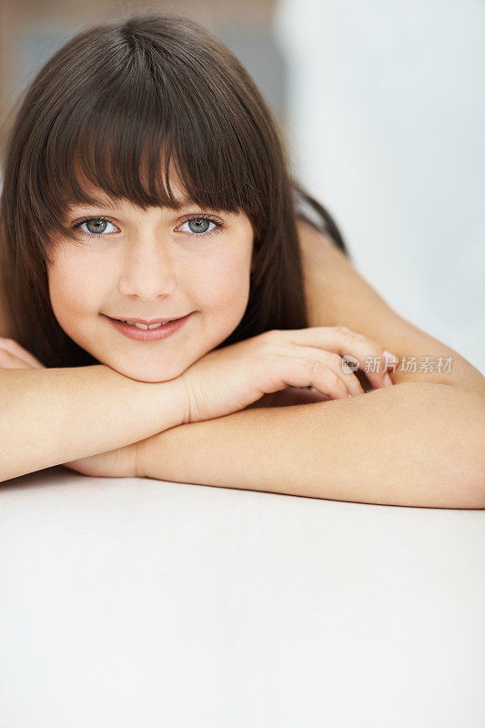 一个可爱的绿眼睛小女孩在室内放松的肖像
