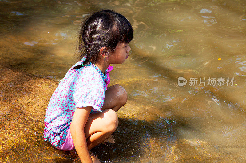 小泰国女孩坐在河边