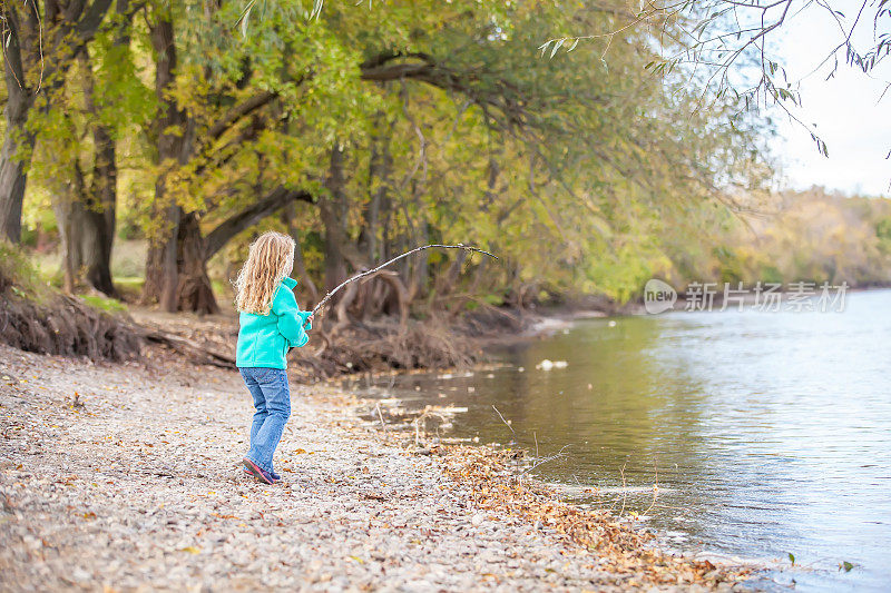 年轻的金发女孩在河岸上玩耍