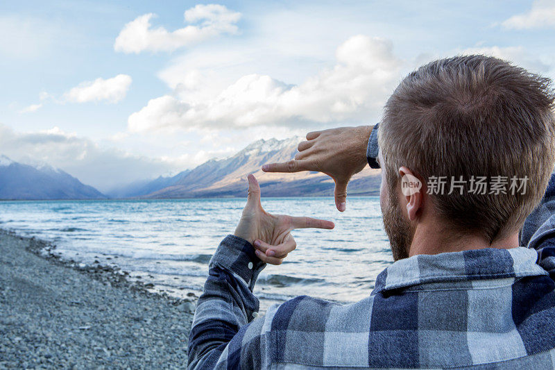 湖边的年轻男子打造了自然的手指框架