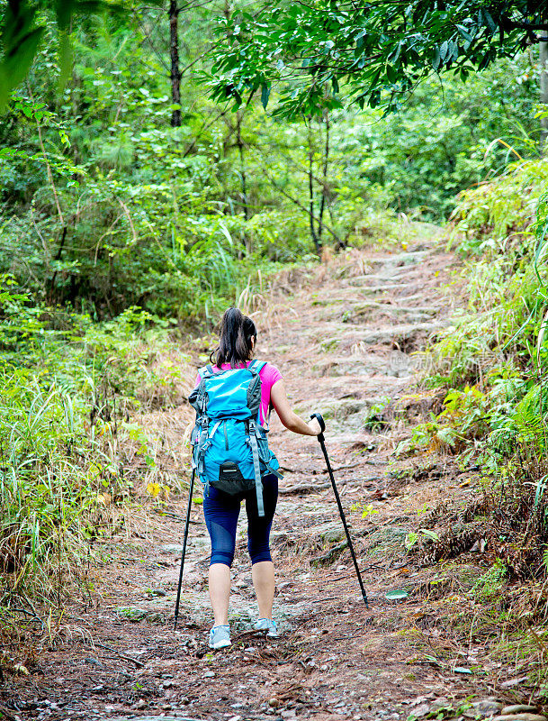 在树林里背着背包的年轻女性徒步旅行者