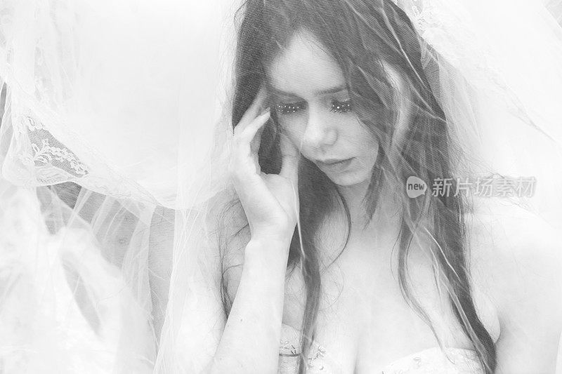 忧伤的年轻新娘身后的薄纱。