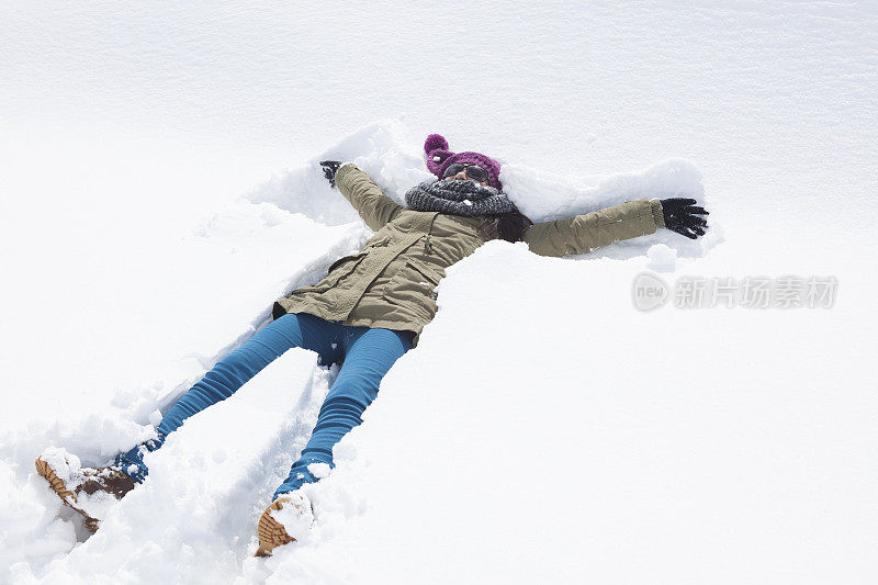 快乐的年轻女子躺在雪地上