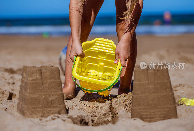 可爱的小女孩在沙滩上建造沙堡