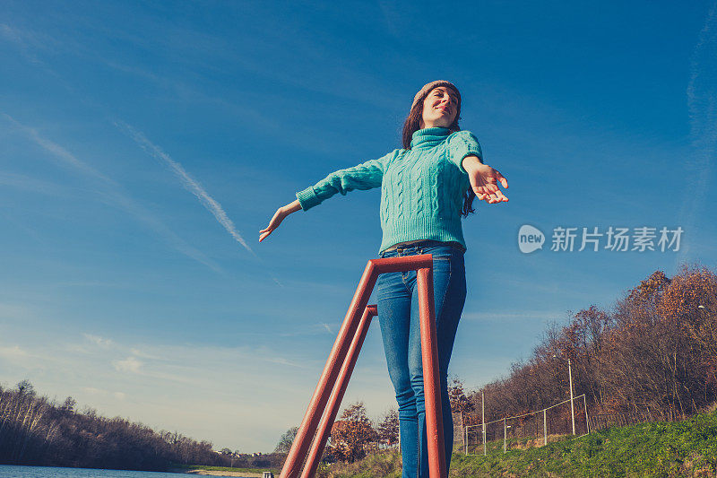 年轻女子躺在湖边的码头上，披着毯子，看日落