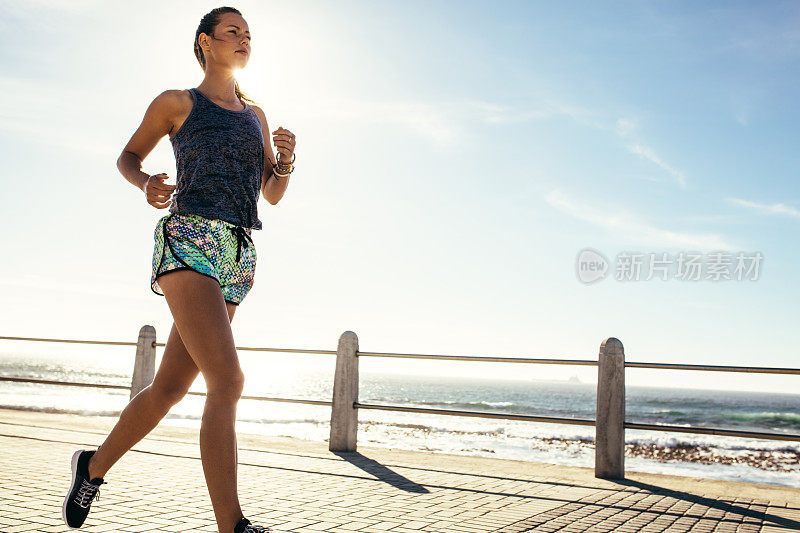 女跑步者沿着海边的道路跑步