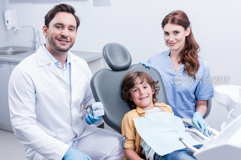 在牙科诊所里，小男孩和微笑的牙医坐在椅子上