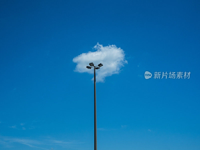 一根灯柱在蓝天上重叠着蓬松的云。