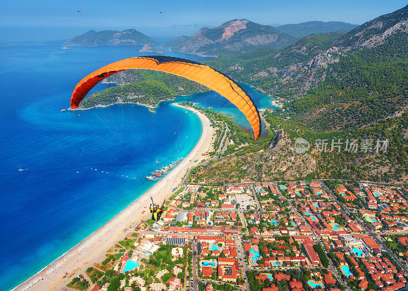 在空中滑翔。在阳光明媚的日子里，双人滑翔伞飞跃大海和碧水群山。鸟瞰图的滑翔伞和蓝色礁湖在Oludeniz，土耳其。极限运动。景观