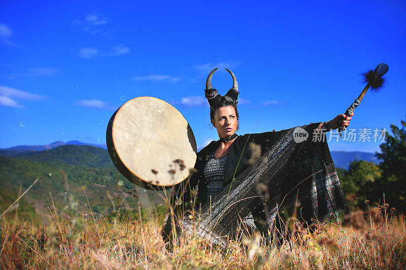 部落异教妇女用鹿角在山上敲着水牛萨满鼓