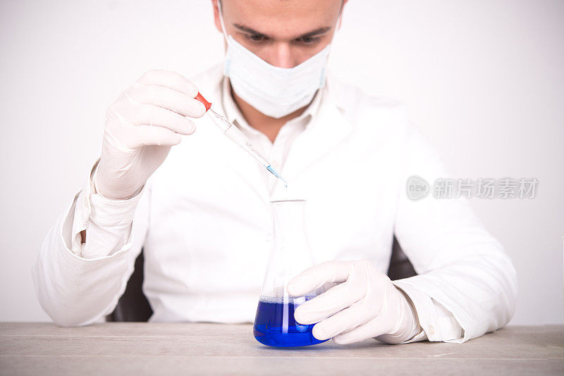 科学家在装有蓝色液体的锥形烧瓶上举着移液管