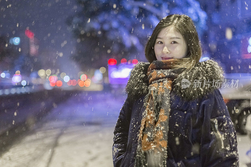 美丽的女人站在雪地里的街道上