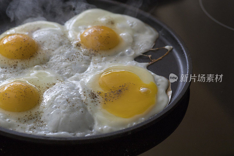 早餐是什么?四个鸡蛋在玻璃陶瓷炉上煮着。