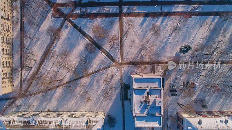 俯视图，正上方鸟瞰被雪覆盖的冬季城市住宅区。复杂的攀爬和旋转摄像机运动