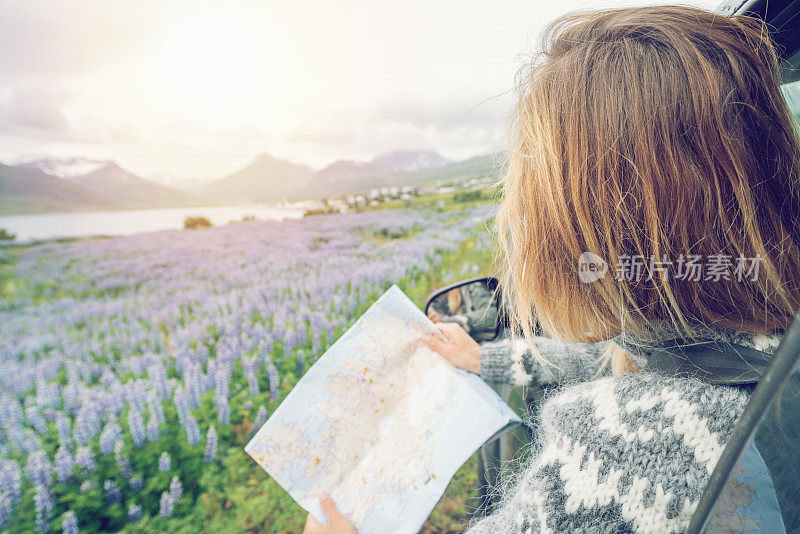 年轻女子在车里看地图，公路旅行的概念假期